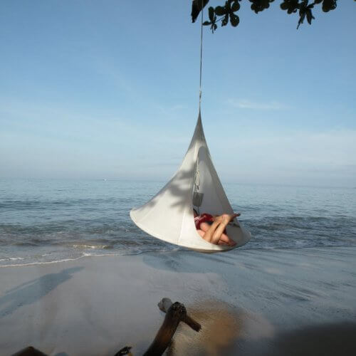 Anwendungsbeispiel - zwei Personen in einem Singel Zelt - dies hängt an einem Baum direkt am Strand - im Hintergrund iund unter dem Zelt ist das Wasser zu sehen Nr.2