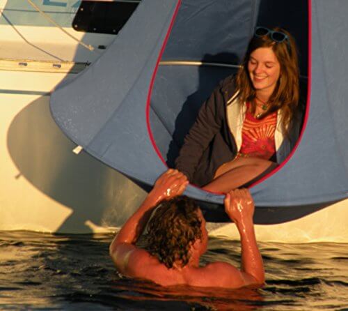 Anwendungsbeispiel - das Hängezelt hängt über Wasser an einem Boot befestigt - ein Mann im Wasser, eine Frau im Hängesessel